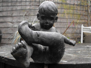 A Whimsical English School Lead Sculpture in the form of a Young Boy Pulling His Sock Off
